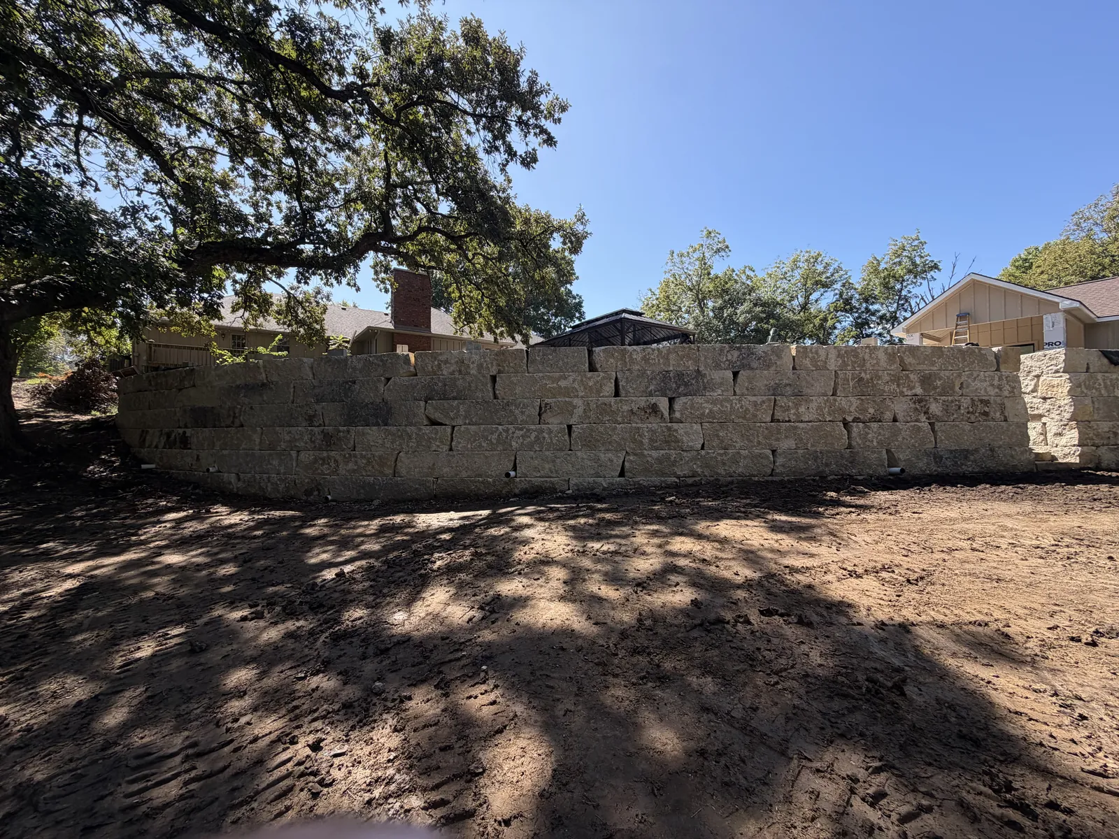 Limestone boulder retaining wall under an oak